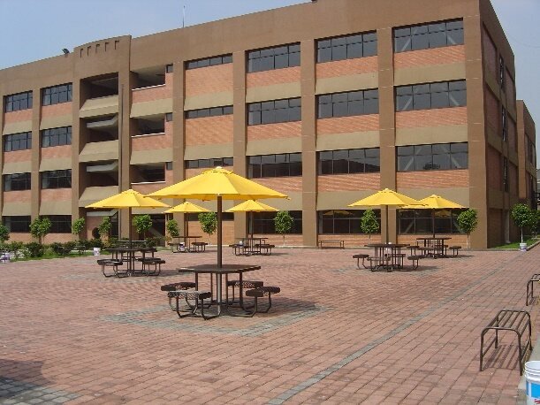 Plaza con sombrillas frente a edificio de aulas