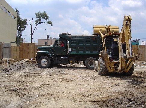 Camión de volteo y retroexcavadora en obra